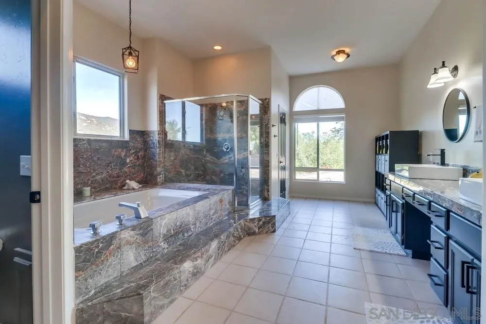15735 Lawson Valley Road Jamul, CA 91935 - Photo 19 of 37 a large spacious bathroom with a granite countertop tub shower and mirror