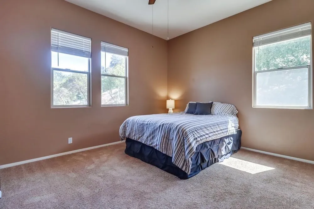 15735 Lawson Valley Road Jamul, CA 91935 - Photo 21 of 37 a spacious bedroom with a bed lamp and window