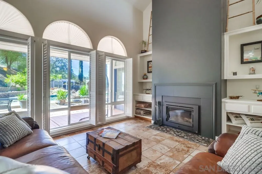 15735 Lawson Valley Road Jamul, CA 91935 - Photo 6 of 37 a living room with furniture a fireplace and a floor to ceiling window
