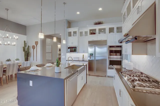a kitchen with kitchen island a counter top space a sink stainless steel appliances and cabinets