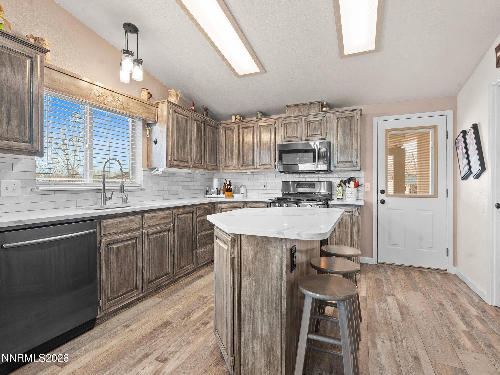 1125 Truckee Lane Fernley, NV 89408 - Photo 6 of 33 a kitchen with kitchen island granite countertop wooden floors and stainless steel appliances