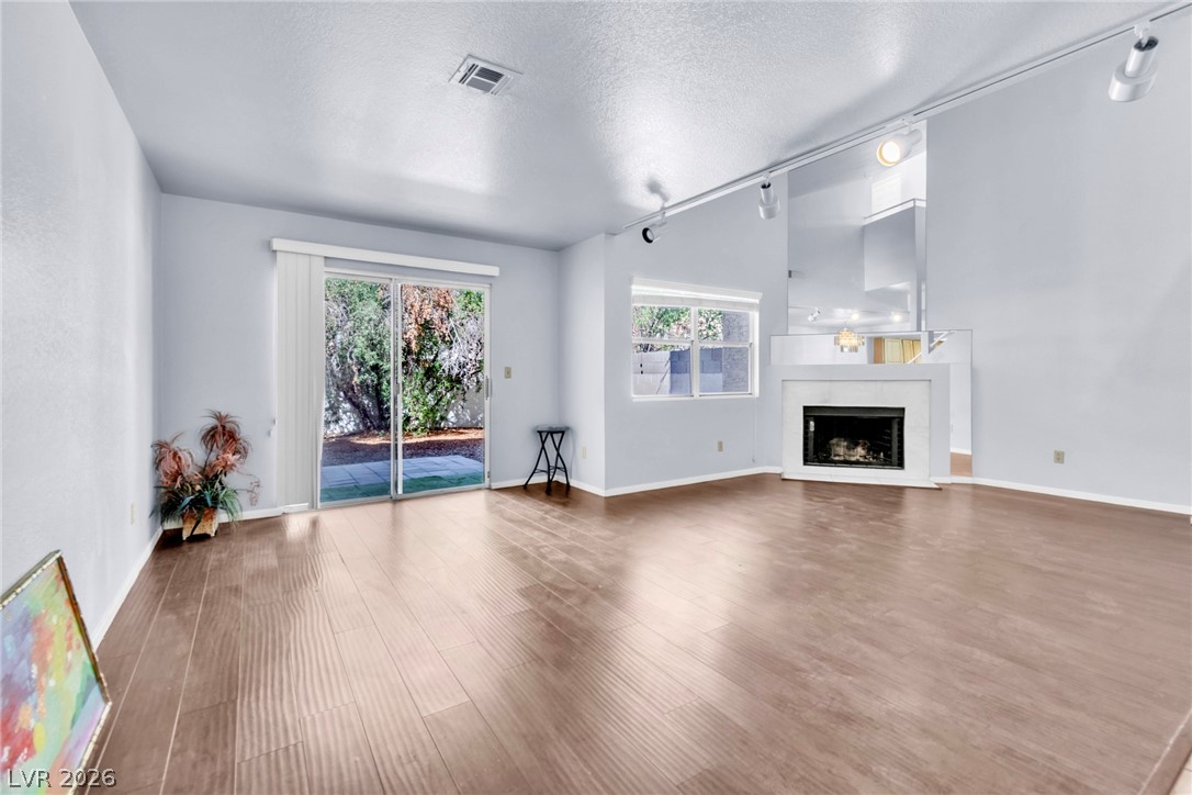 6250 West Flamingo Road, Unit 98 Las Vegas, NV 89103 - Photo 12 of 40 Unfurnished living room with a fireplace, wood finished floors, a textured ceiling, rail lighting, and visible vents
