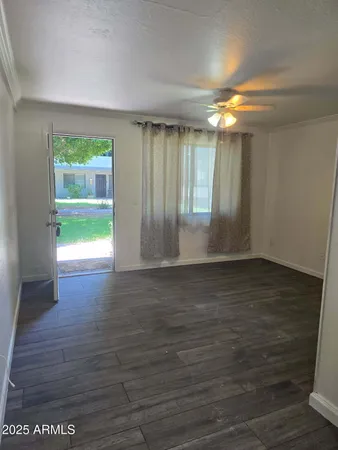a view of empty room with wooden floor and fan