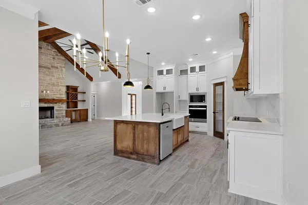 a large kitchen with stainless steel appliances kitchen island wooden floors granite counter tops and a view of living room