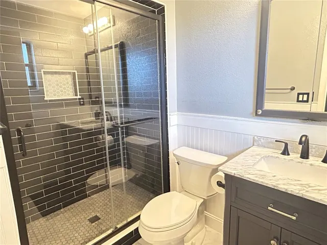 a bathroom with a granite countertop sink toilet and shower
