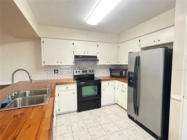 a kitchen with granite countertop a refrigerator stove and sink