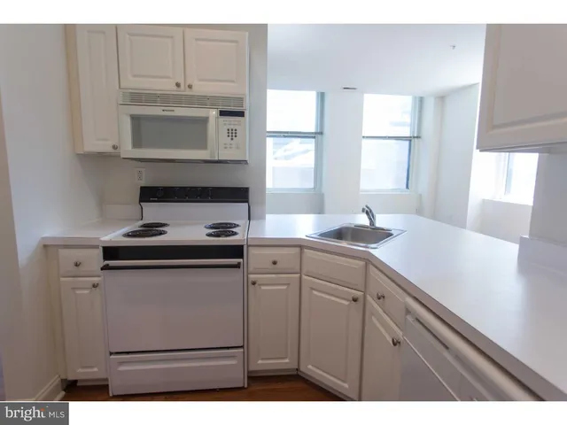 a kitchen with stainless steel appliances granite countertop a sink a stove and white cabinets