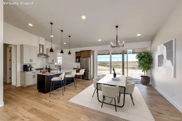 a dining room with wooden floor and kitchen view