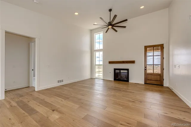 an empty room with wooden floor fireplace and windows