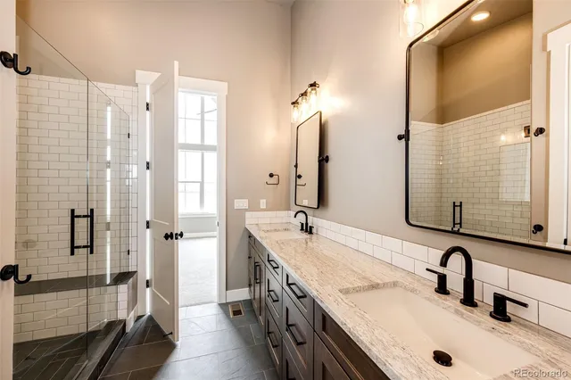 a bathroom with a granite countertop double vanity sink and mirror