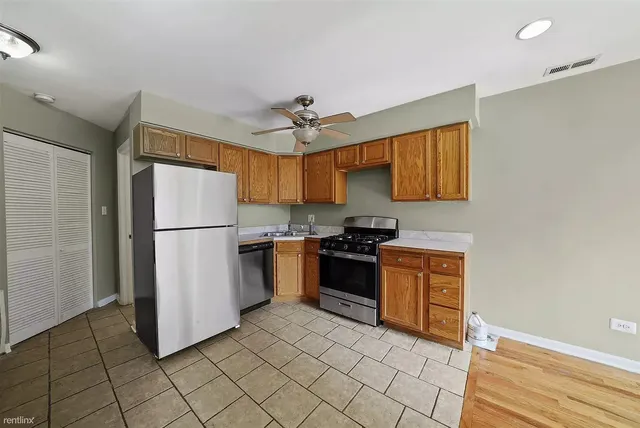 a kitchen with a refrigerator a stove top oven and cabinets