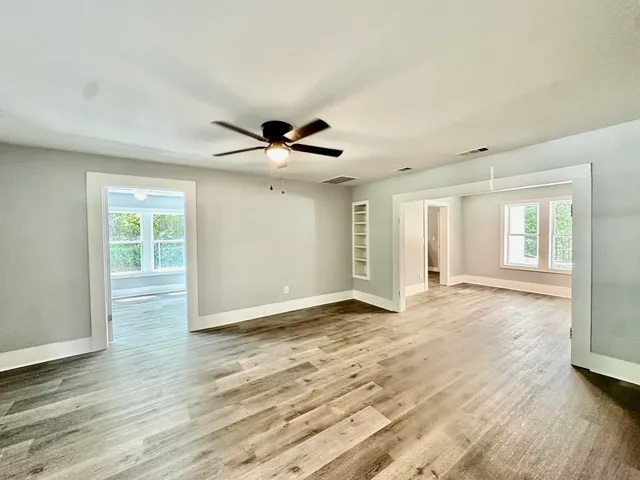 a view of an empty room with wooden floor and a window