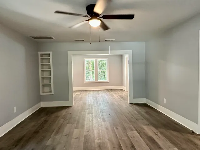 a view of empty room with wooden floor and fan