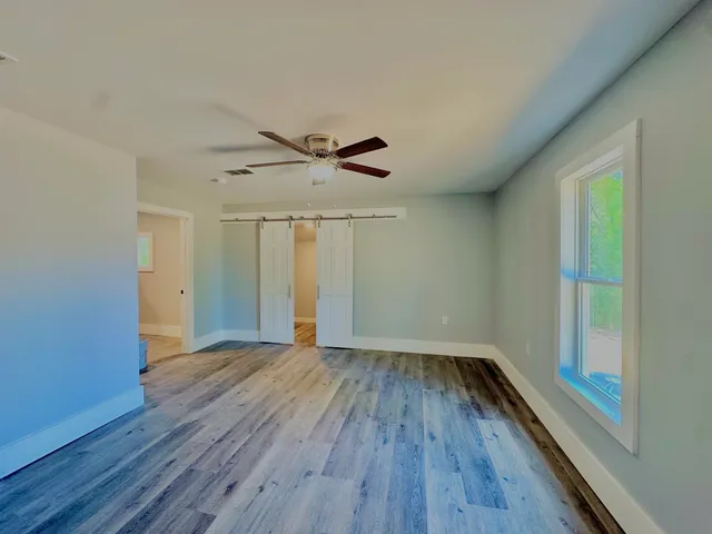 a view of an empty room with wooden floor and a window