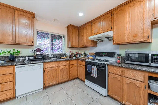a kitchen with stainless steel appliances granite countertop wooden cabinets a stove a sink and dishwasher