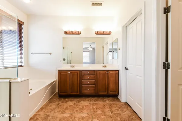 a bathroom with a vanity a sink a mirror a bathtub and window