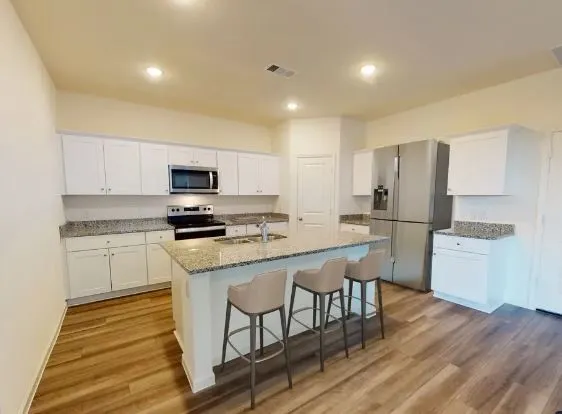 a kitchen with a sink a stove a refrigerator and white cabinets