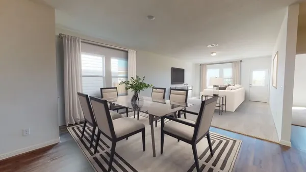 a living room with stainless steel appliances furniture a flat screen tv and kitchen view