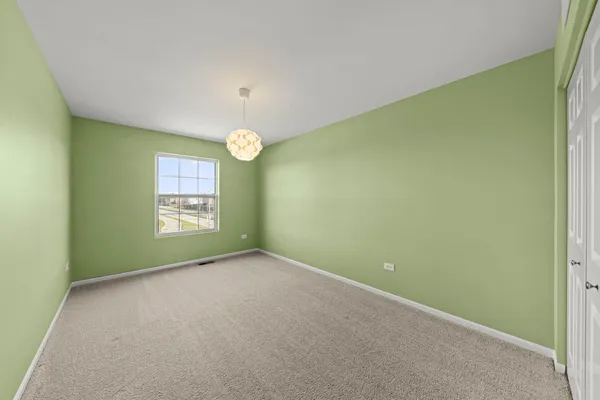 an empty room with windows and chandelier fan