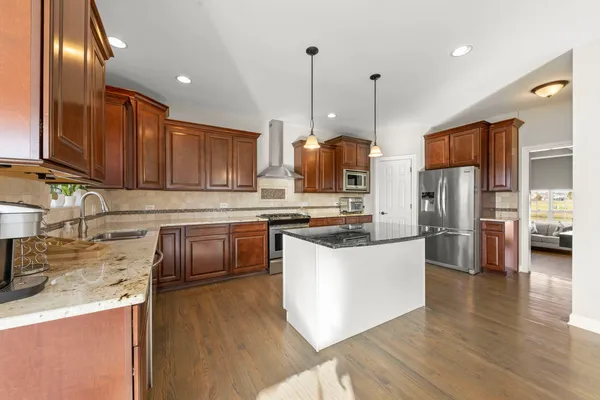 a kitchen with stainless steel appliances granite countertop a sink a stove and a refrigerator