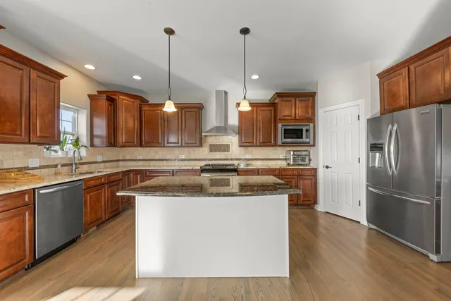 a kitchen with stainless steel appliances granite countertop a sink a stove and a refrigerator