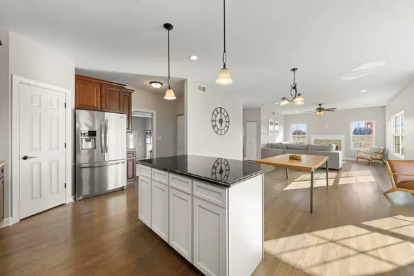 a kitchen with granite countertop a stove a refrigerator a oven a dining table and chairs with wooden floor