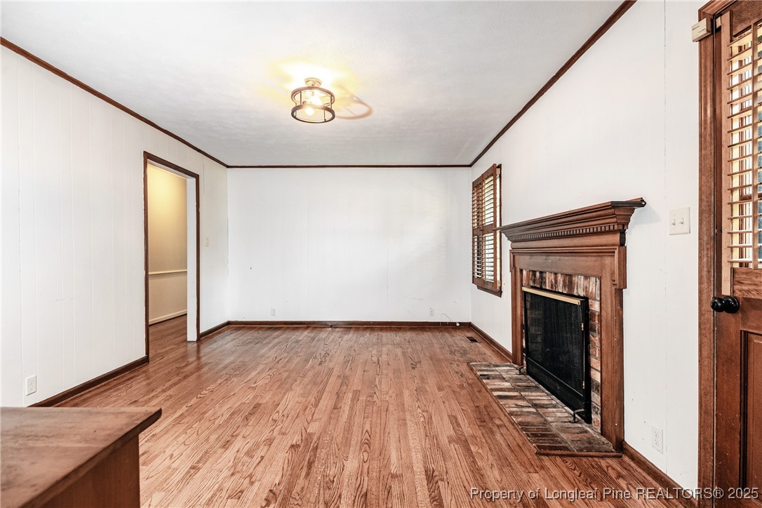 2818 Millbrook Road Fayetteville, NC 28303 - Photo 13 of 32 a view of an empty room with wooden floor and a fireplace