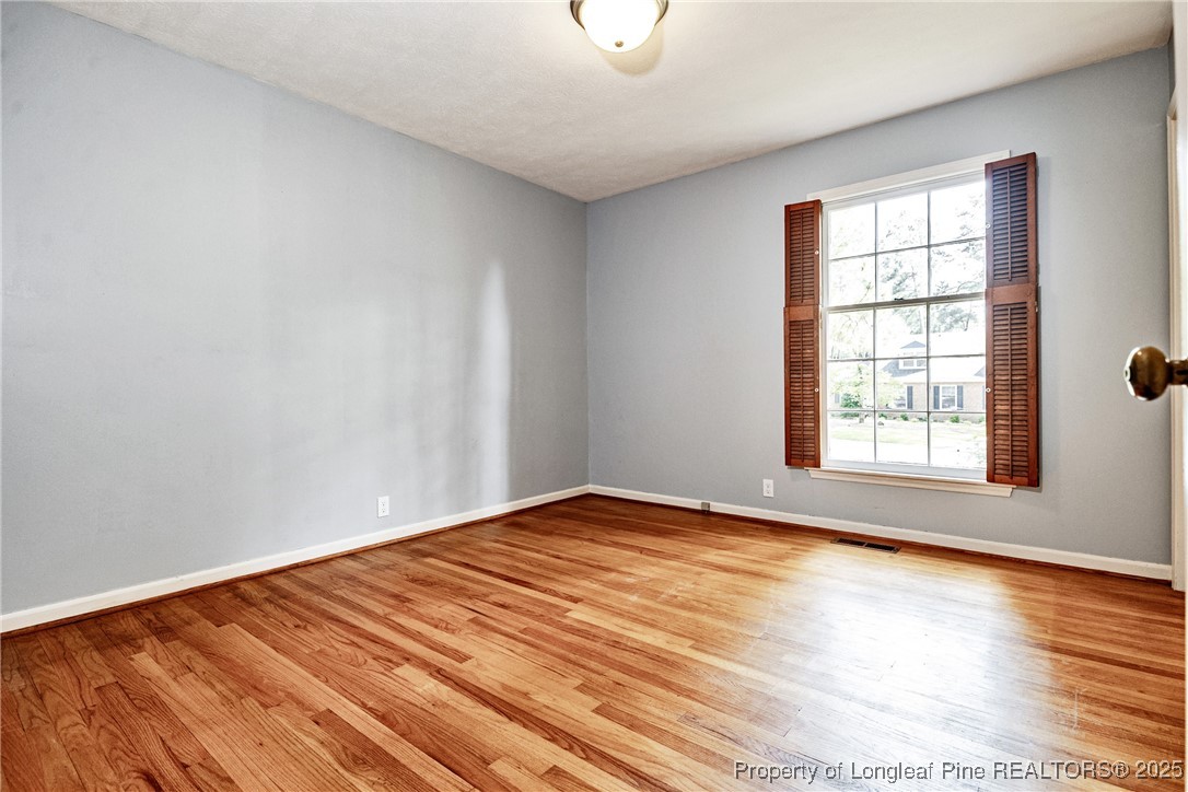 2818 Millbrook Road Fayetteville, NC 28303 - Photo 23 of 32 a view of an empty room with wooden floor and a window