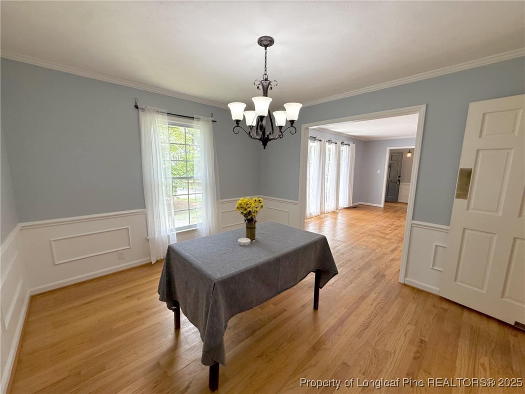 2818 Millbrook Road Fayetteville, NC 28303 - Photo 10 of 32 a dining room with wooden floor a chandelier a wooden table and chairs