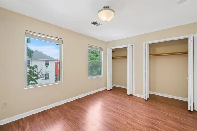 an empty room with wooden floor and windows