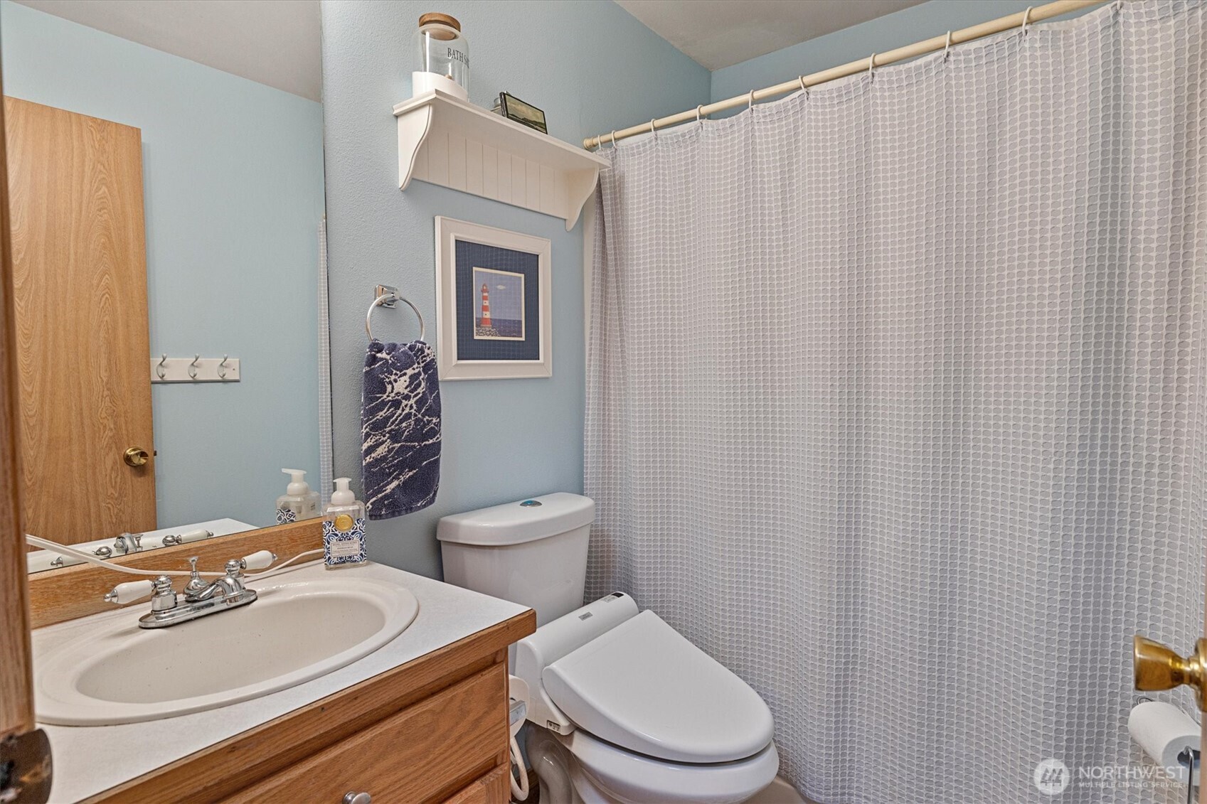 6352 24th Avenue Southwest Seattle, WA 98106 - Photo 14 of 31 a bathroom with a sink a toilet a mirror and shower curtain