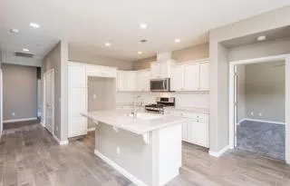 a kitchen with stainless steel appliances kitchen island a sink a stove a refrigerator and white cabinets
