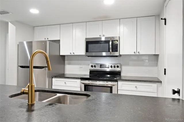 a kitchen with granite countertop a stove a sink and a microwave