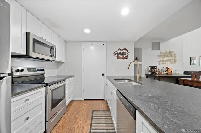 a kitchen with stainless steel appliances granite countertop a stove white cabinets a sink and dishwasher
