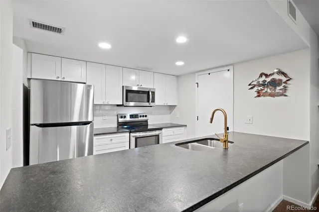 a kitchen with stainless steel appliances a refrigerator a sink a stove a microwave and cabinets