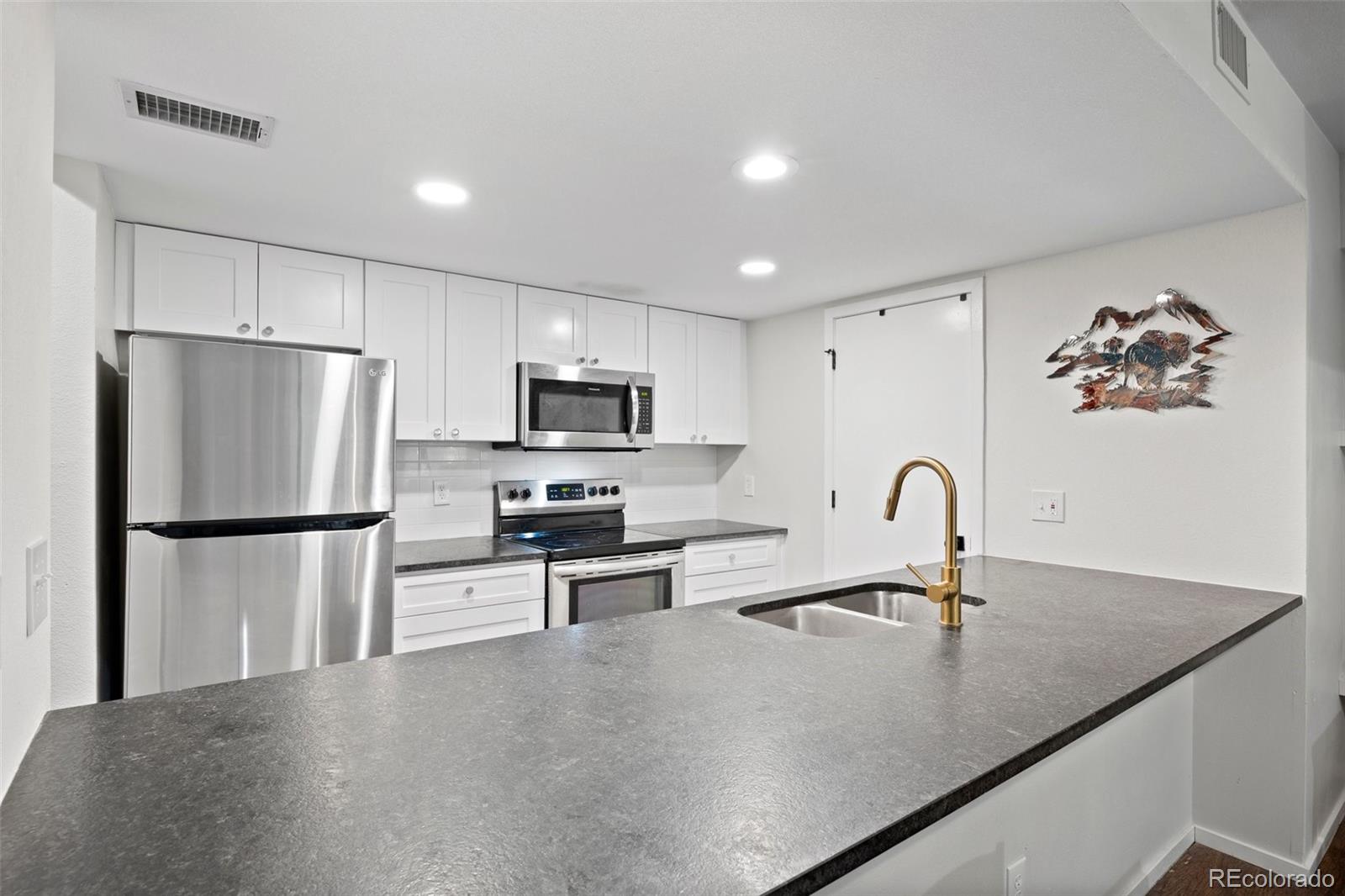 23551 Genesee Village Road, Unit H Golden, CO 80401 - Photo 18 of 40 a kitchen with stainless steel appliances a refrigerator a sink a stove a microwave and cabinets