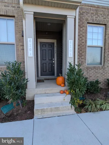 a view of a front door of the house with potted plants