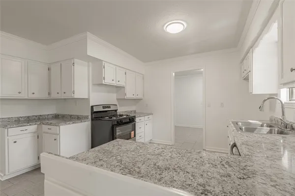 a kitchen with granite countertop a sink stove and refrigerator