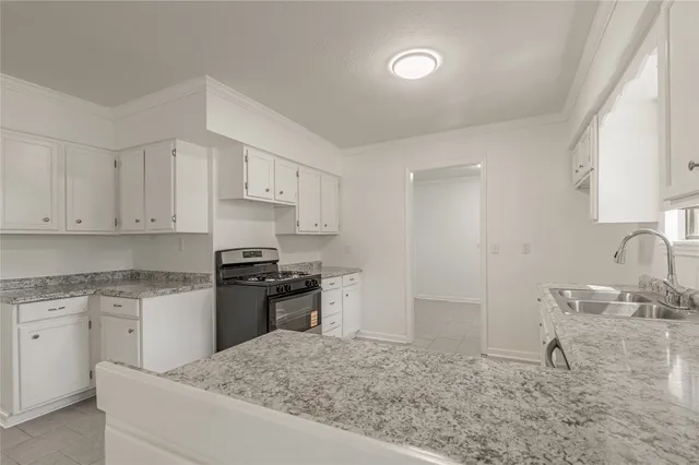 a kitchen with granite countertop a sink stove and refrigerator