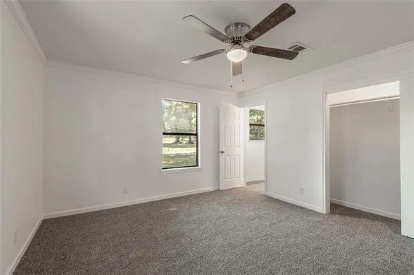 an empty room with windows and fan