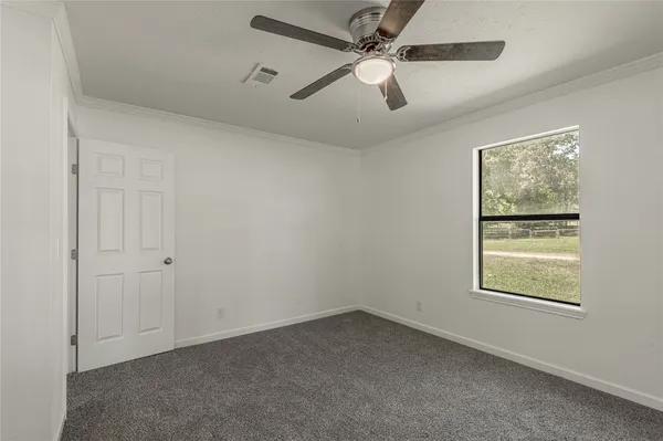 an empty room with a window and a fan