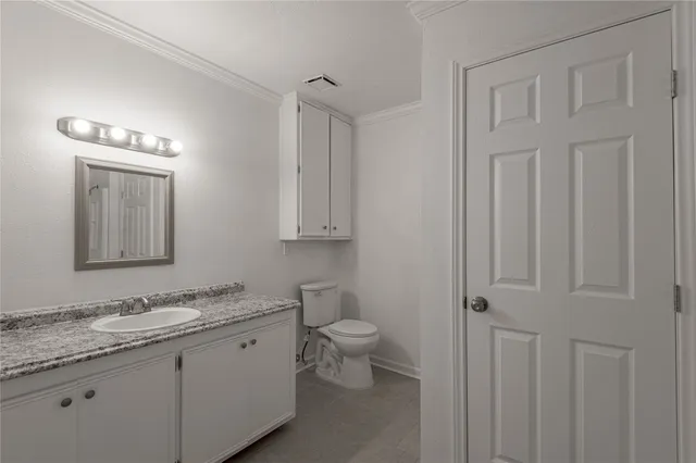 a bathroom with a granite countertop sink toilet and mirror
