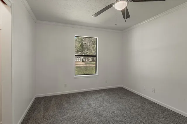 an empty room with a window and ceiling fan