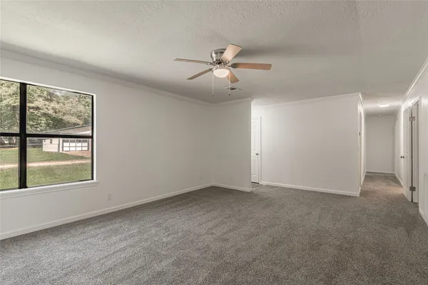 an empty room with chandelier fan and windows