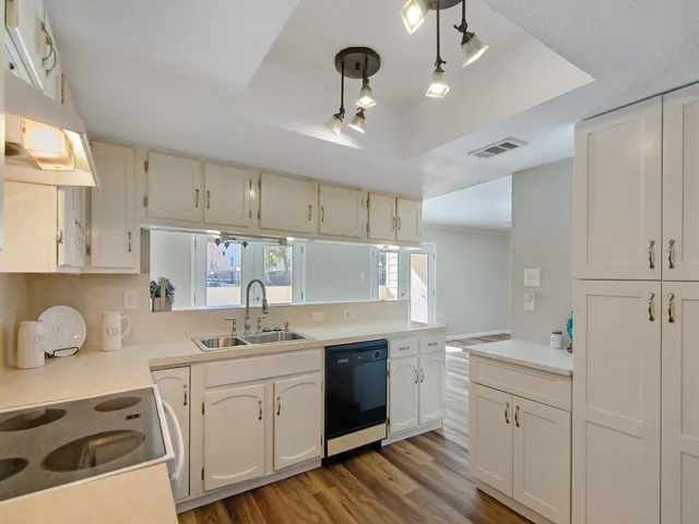 a kitchen with white cabinets appliances and a window