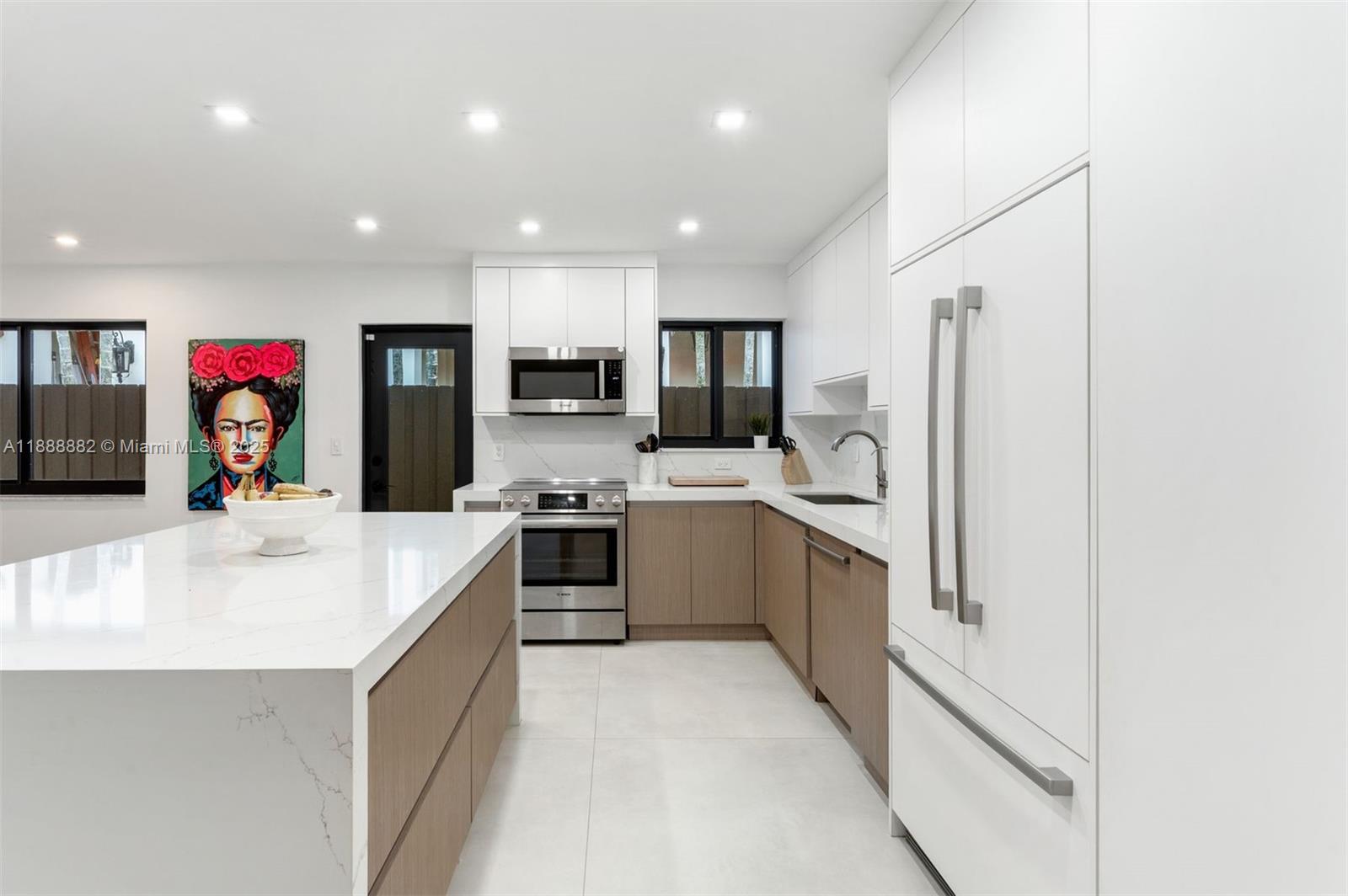 420 Southwest 19th Road Miami, FL 33129 - Photo 7 of 32 a large white kitchen with stainless steel appliances granite countertop a sink a stove top oven a refrigerator and cabinets