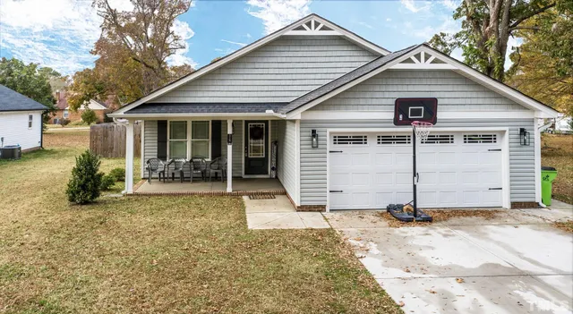 a view of a house with a yard and lawn chairs under an umbrella