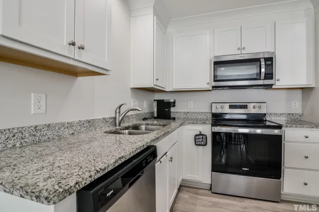 a kitchen with granite countertop white cabinets and chairs