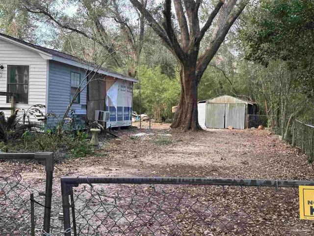 a backyard of a house with wooden fence and large trees