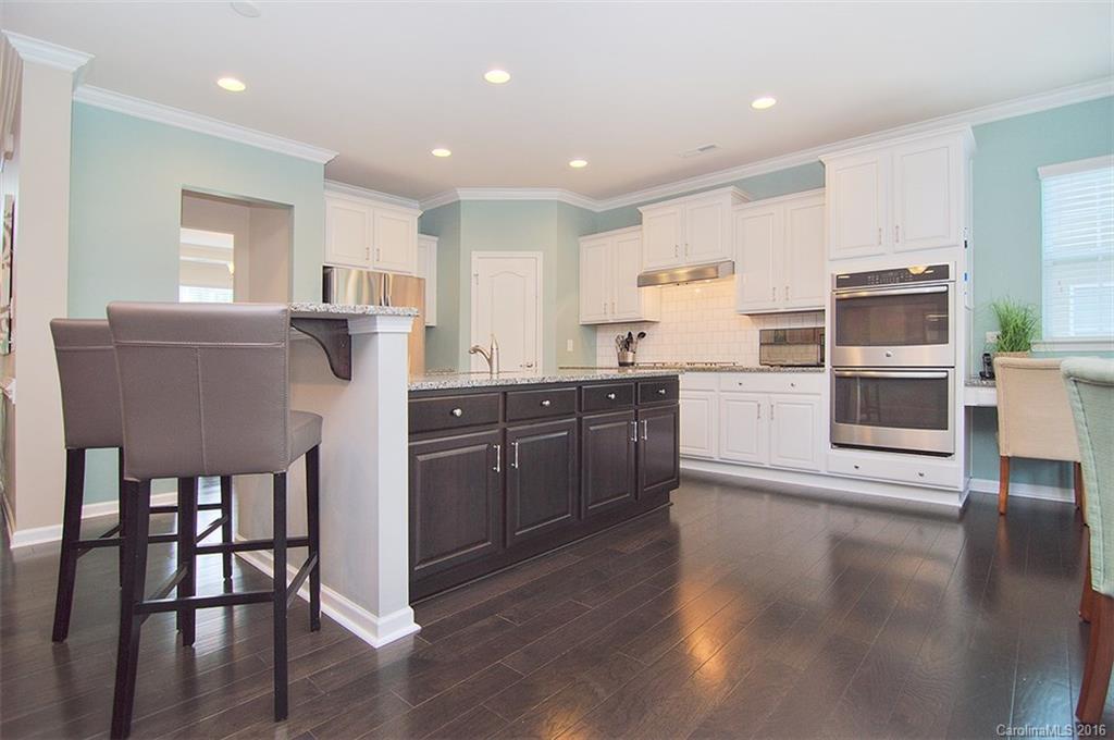 565 Brookhaven Drive Fort Mill, SC 29708 - Photo 5 of 24 a kitchen with stainless steel appliances kitchen island granite countertop a stove a refrigerator a sink a dining table and chairs with wooden floor